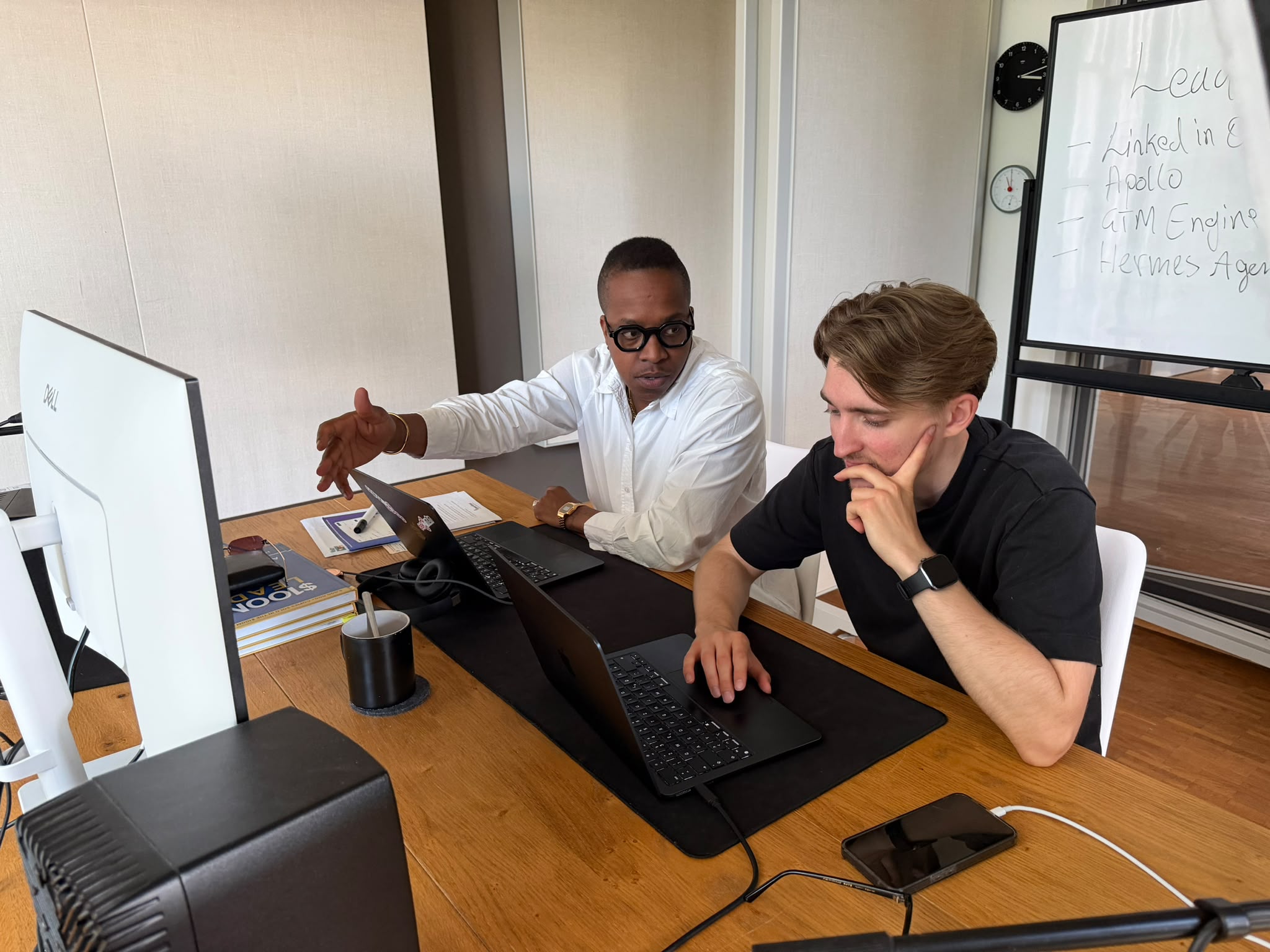Patrick Mashegwana and Henrik Horn working together at a desk with laptops, planning GTM engineering workflows on a whiteboard behind them
